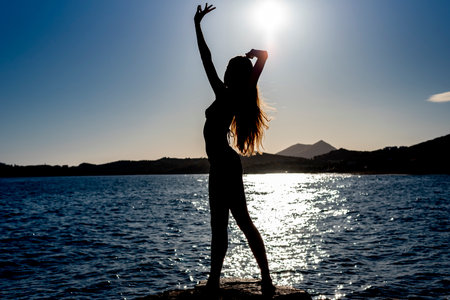 beautiful shadowed female woman with long hair posing under the sunの写真素材