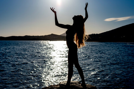 beautiful shadowed female woman with long hair posing under the sunの写真素材