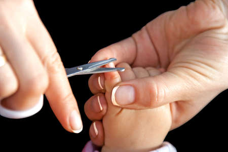 Mother cutting nails with scissors isolated on blackの写真素材