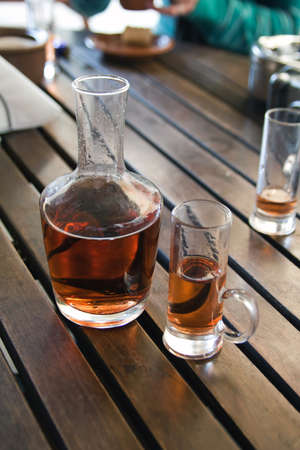 Glass and bottle with plum tincture on wooden tableの写真素材