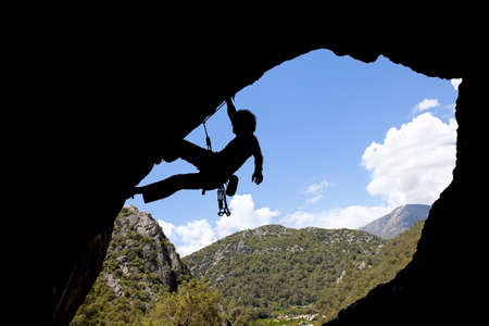 Rock climber silhouette in a sunny day climbing highの写真素材