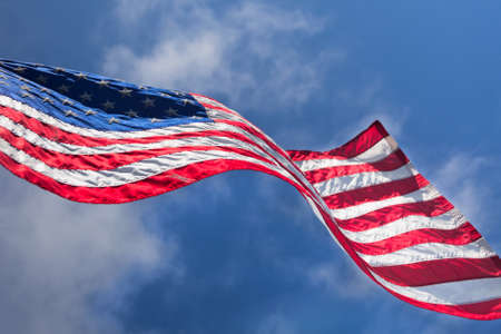 USA flag waving on the wind on cloudy sky background