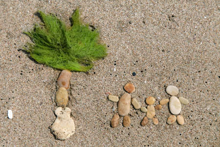 Happy family and palm tree made from stone on the sand beachの写真素材