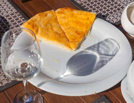 Imeretian khachapuri on white dish and glass reflection