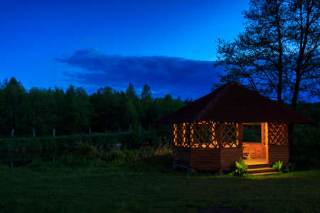 Wooden gazebo on the river bank at nightの写真素材