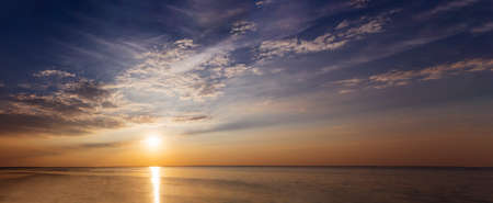 Sunset with sun rays and clouds in the sea panoramaの写真素材