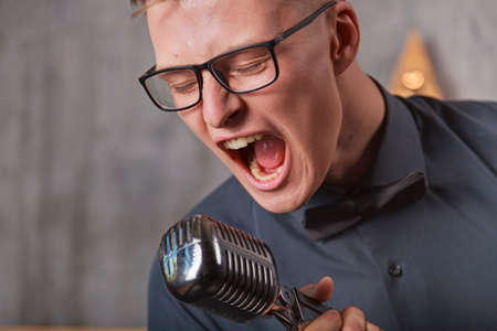 Young man singing with vintage microphoneの写真素材
