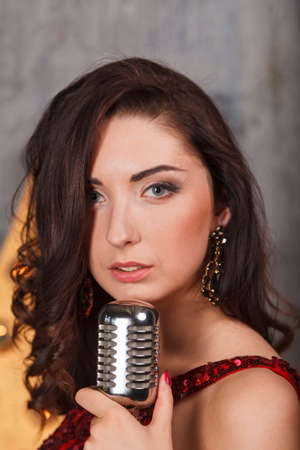 Young girl in red cocktail dress singing with vintage microphoneの写真素材