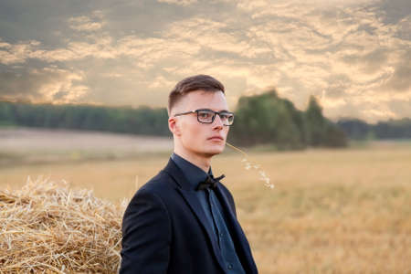 Young man with glasses thinking and standing on the fieldの写真素材