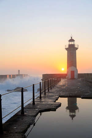 Lighthouse Felgueirasin Porto with wave splash at sunset, Porto, Portugalの写真素材