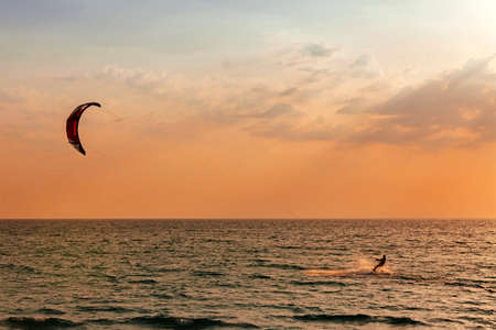 Kite surfer sailing in the sea at sunset oceanの写真素材