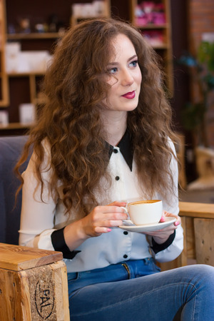Beautiful girl with coffee sitting in a chairの写真素材