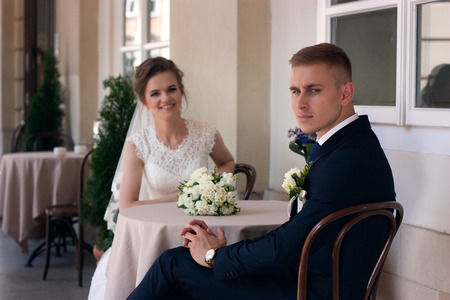 The groom looks at the camera while sitting at a table with the brideの写真素材