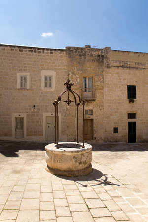 A small square with a fountain in the historical medieval city of Mdina on Malta.の写真素材