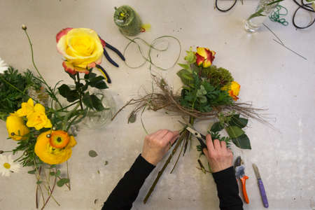 A florist prepares a bouquet with red and yellow roses.
