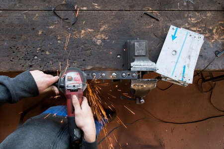 A locksmith whetting a piece of metal. Hot sparks flying in all directions.