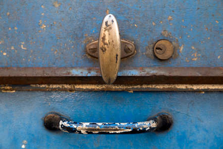 Closeup of the lid of a rusty blue metal tool box. The two handles and the key hole form a smiling faceの写真素材