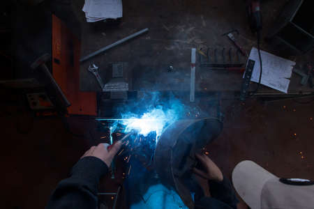 A metal worker welding different metal parts on a table according instructions.の写真素材