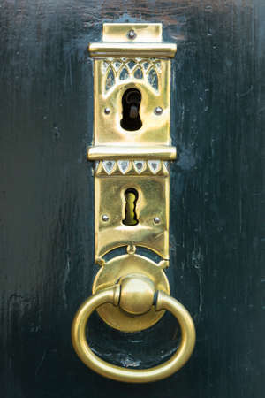 A dark green painted wooden door with a beautifully forged golden key holeの写真素材