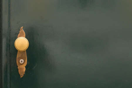 A dark green painted door with bronze door bells and a golden round door knob. Free space on the right side of the image.の写真素材