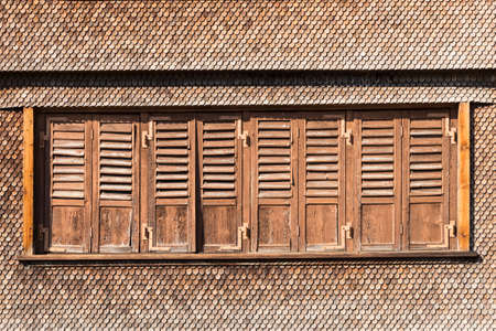 Detail of an old swiss chalet with shingles and withered wooden window shuttersの写真素材