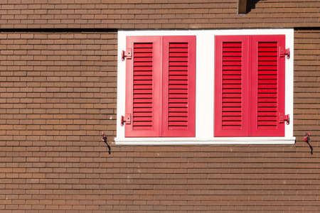 Closeup of a swiss chalet with brown wall, white frame and red window shuttersの写真素材