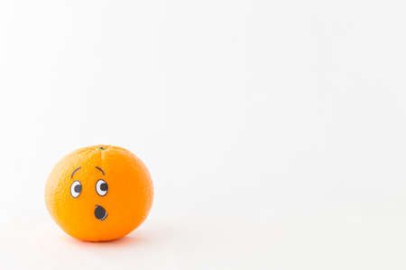 An orange in front of white background with a funny face showing astonishmentの写真素材