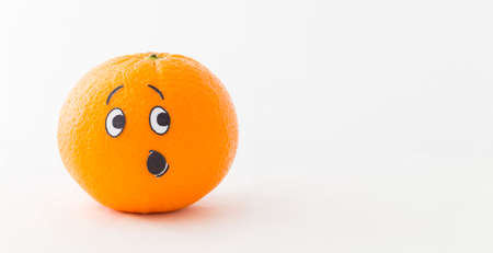 An orange in front of white background with a funny face showing astonishmentの写真素材