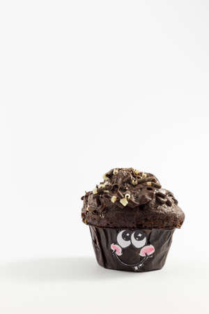A fresh and sweet chocolate muffin with cute cartoon style face on white backgroundの写真素材