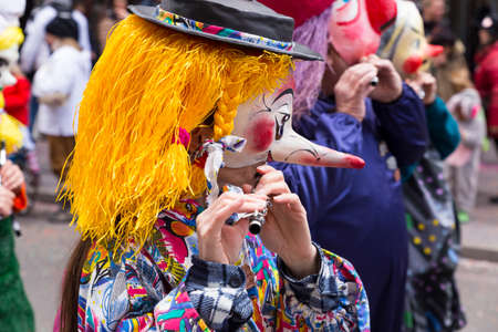 Basel carnival. Freie Strasse, Basel, Switzerland - March 7, 2017. Closeup of a single carnival participant wearing a mask with blond hair and long nose, playing piccolo and marching with his group in the streetsのeditorial素材