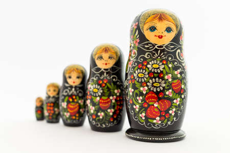 Beautiful black matryoshka dolls with white, green and red painting in front of light backgroundの写真素材
