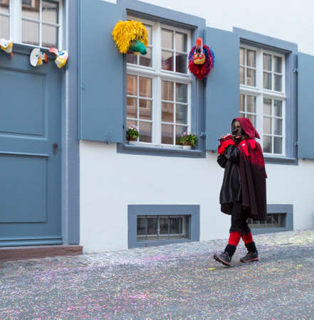 Basel carnival. Nadelberg, Basel, Switzerland - March 7, 2017. A single carnival participant playing piccolo while marching alone through the old town.のeditorial素材