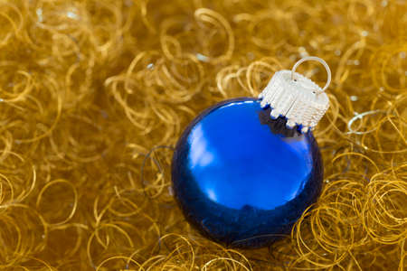 Shiny blue christmas ball on curly gold glitterの写真素材