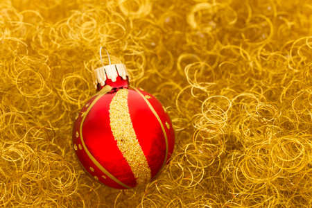 Beautiful gold and red decorated christmas ball on curly gold glitterの写真素材