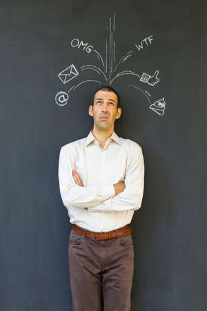 Single white adult man standing in front of a blackboard with drawn social media icons symbolizing...