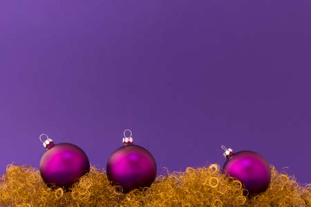 Beautiful purple christmas balls with satin effect on gold glitter and purple background.