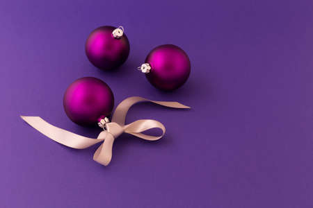 Beautiful purple christmas balls with satin effect and grey gift ribbon on purple background.の写真素材