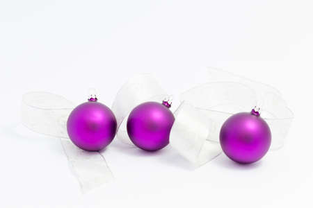 Beautiful glossy purple christmas balls with white and silver ribbon on white backgroundの写真素材