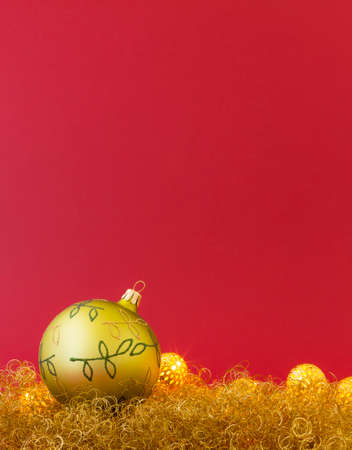 Beautiful hand painted green christmas ball on gold glitter with led lights and red background.の写真素材