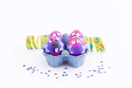 Group of colorful painted Easter eggs with funny cartoon style faces in a light blue egg box,...
