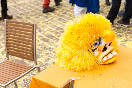 Basel carnival 2018. Gerbergasse, Basel, Switzerland - February 19th, 2018. Close-up of a single yellow carnival mask laying on a restaurant tableのeditorial素材