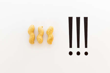 Concept of the saying that's peanuts! Raw unpeeled peanuts and black ink hand writing on white paper...