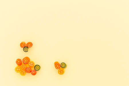 Assortment of colorful sweet handmade candy pieces arranged on light yellow paperの写真素材