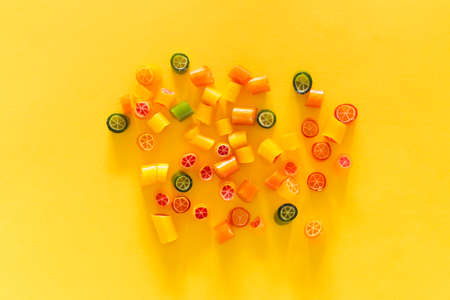 Assortment of colorful sweet handmade candy pieces arranged on yellow paperの写真素材