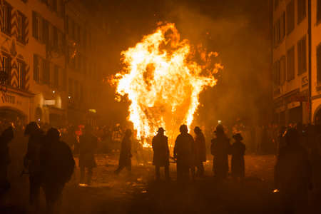 Chienbaese festival. Switzerland, Liestal, Rathausstrasse 25, 18th of February 2018. Festival participants pulling a wagon stacked with burning wood through the old town.のeditorial素材