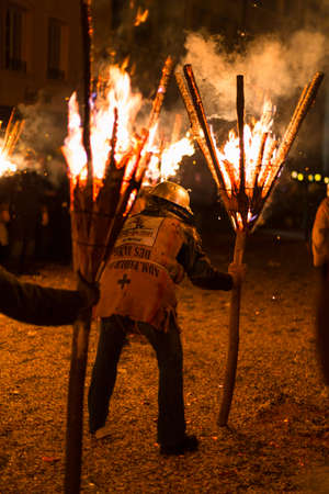 Chienbaese festival. Switzerland, Liestal, Rathausstrasse 25, 18th of February 2018. Festival participants carrying burning broom shaped wooden logs on their shoulders through the old town.のeditorial素材