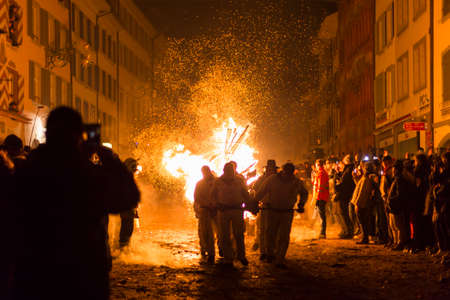 Chienbaese festival. Switzerland, Liestal, Rathausstrasse 25, 18th of February 2018. Festival participants pulling a wagon stacked with burning wood through the old town.のeditorial素材
