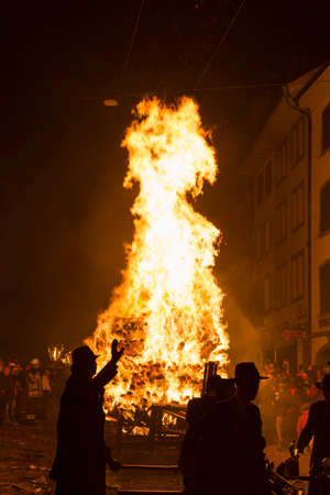 Chienbaese festival. Switzerland, Liestal, Rathausstrasse 25, 18th of February 2018. Festival participants pulling a wagon stacked with burning wood through the old town.のeditorial素材