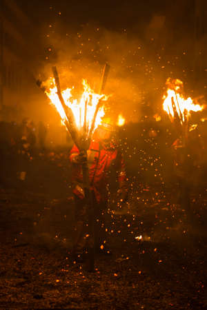 Chienbaese festival. Switzerland, Liestal, Rathausstrasse 25, 18th of February 2018. Festival participants carrying burning broom shaped wooden logs on their shoulders through the old town.のeditorial素材
