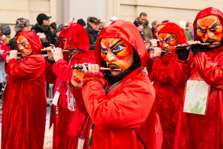 Steinenberg, Basel, Switzerland - February 19th, 2018. Close-up of carnival participants in bright red costumes playing piccolo fluteのeditorial素材